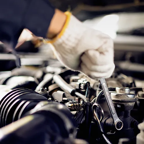 Auto mechanic tightening engine components with a wrench during a vehicle repair.