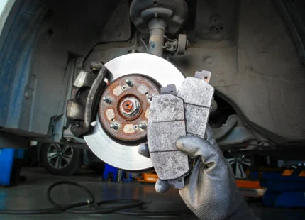 Uncle Al's technician performing a brake inspection, holding up brake pads