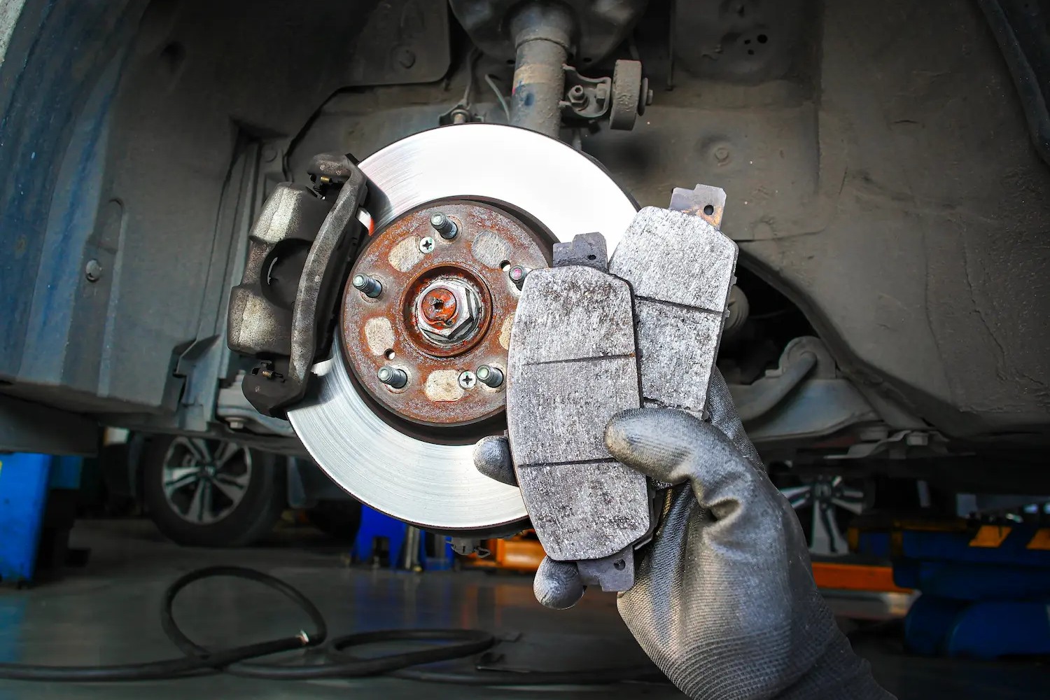 Uncle Al's technician performing a brake inspection, holding up brake pads